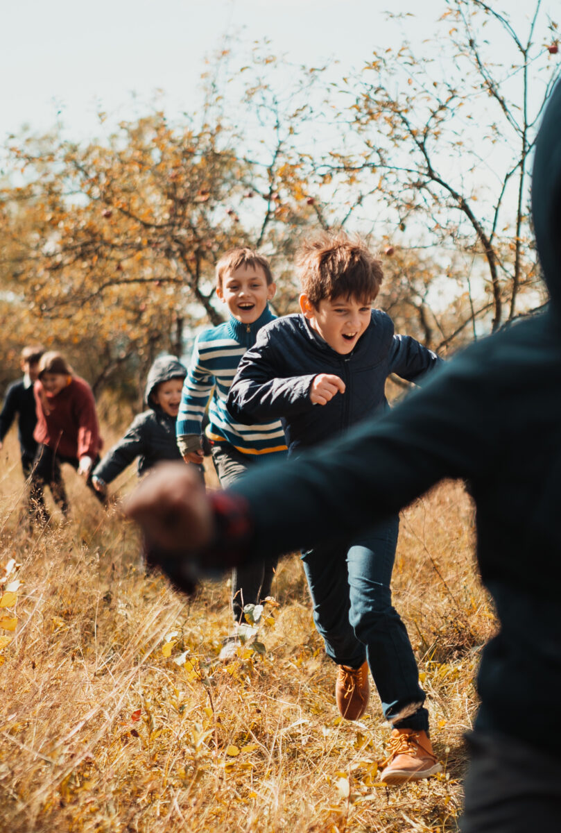 Six children smiling and running through the woods