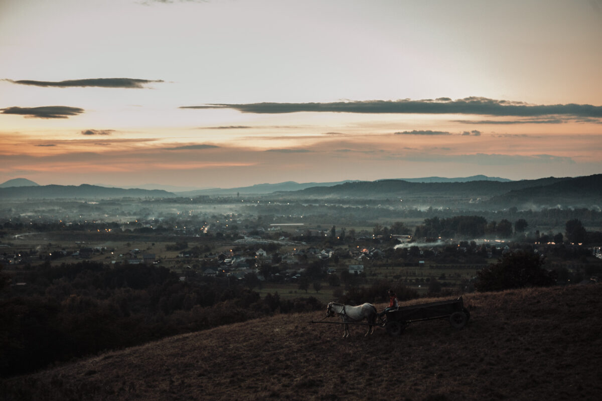 Drone shot of a village at sunset with a horse drawn carriage in view