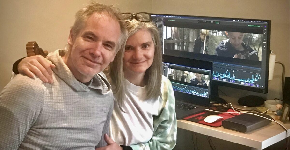 Mark and Christine Haslett sit infront of a computer screen showing Izidor footage being edited.
