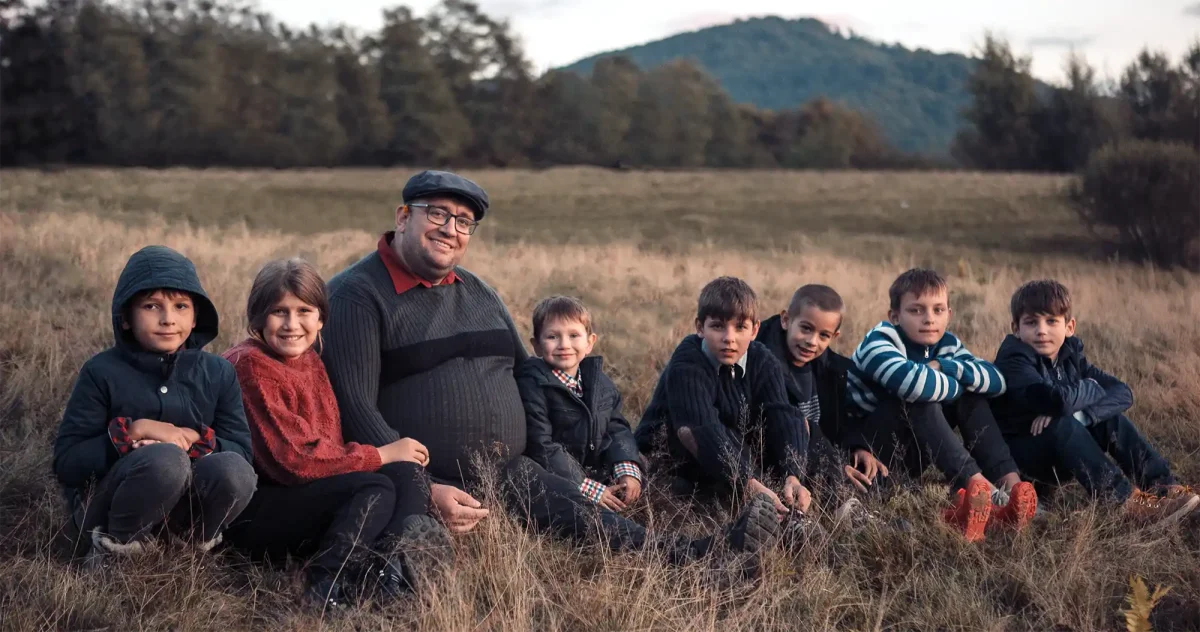 Dragos and child actors sitting in a field at sunset